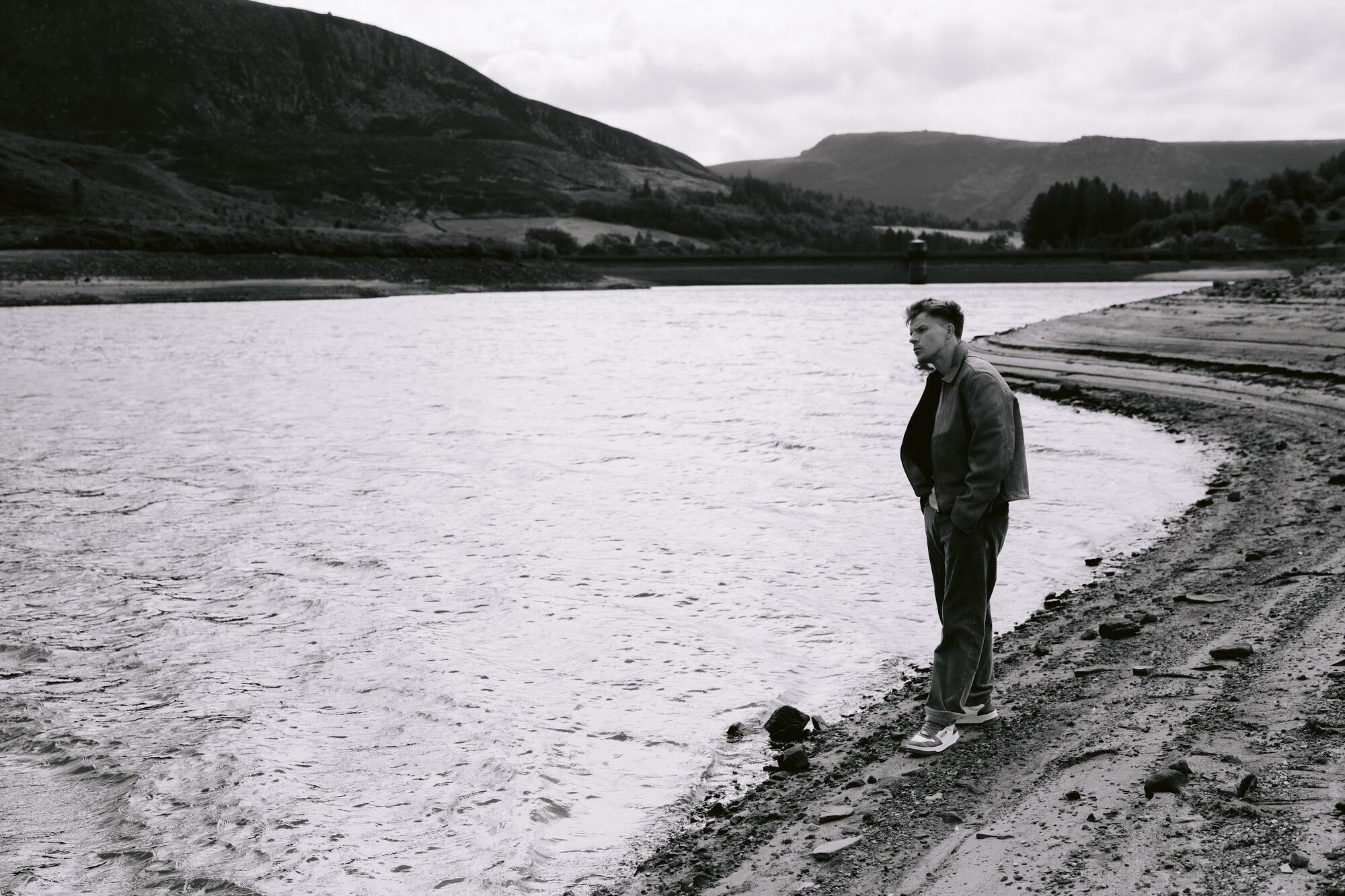Nathan Grisdale walking the shoreline of a reservoir