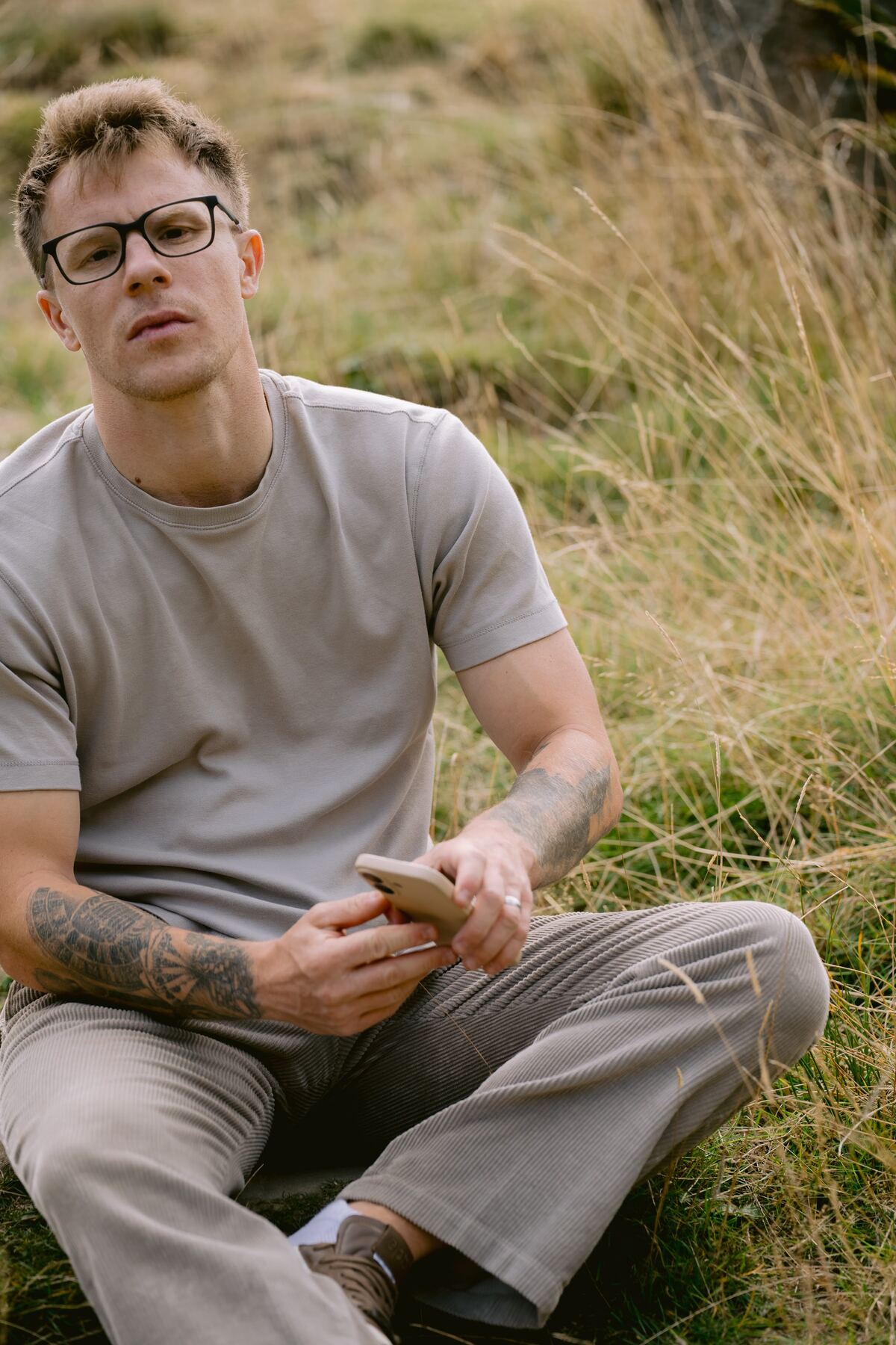 Nathan Grisdale sitting in long grass on a hillside